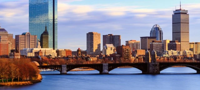 Horizonte urbano reflejado en río con puentes iluminados al atardecer