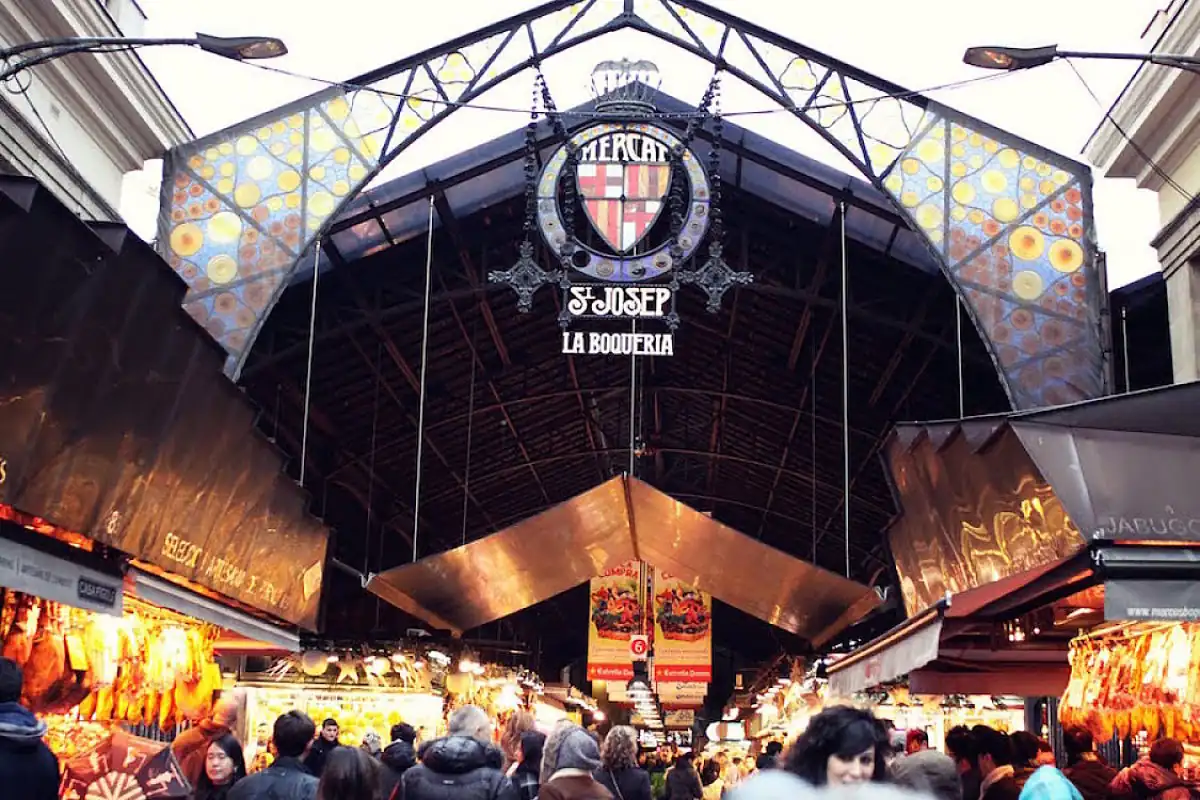 Entrada iluminada del Mercado de La Boquería con multitud de vendedores