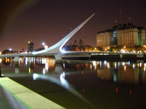 Escultura moderna blanca junto a agua al atardecer con reflejo