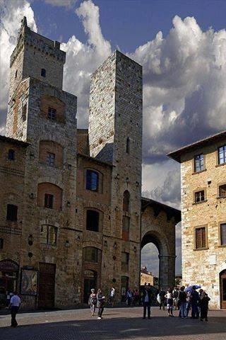 Plaza medieval con torres altas de piedra y arco de entrada