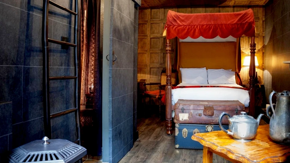 Dormitorio con cama de dosel rojo y decoración medieval en tema Harry Potter