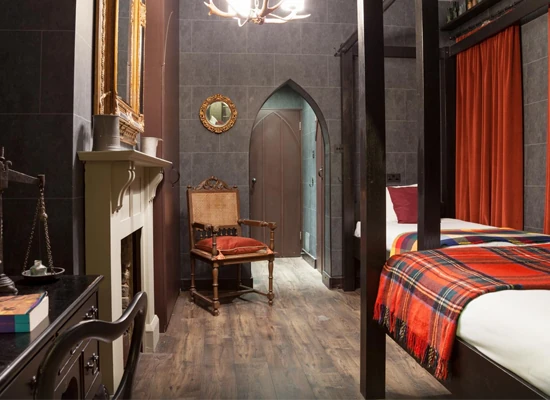 Cuarto con puerta arqueada, cama con edredón a cuadros y paredes oscuras