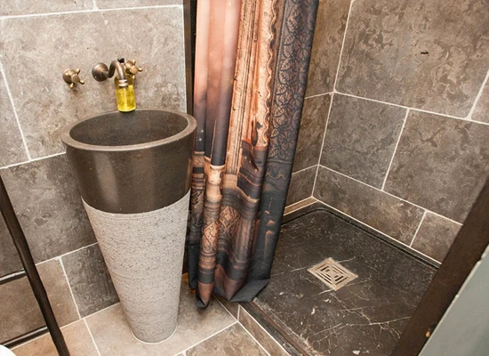 Baño moderno con lavabo cilíndrico y azulejos grises