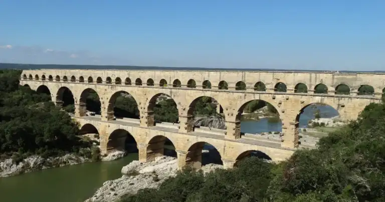 Acueducto romano de múltiples arcos sobre río rodeado de vegetación