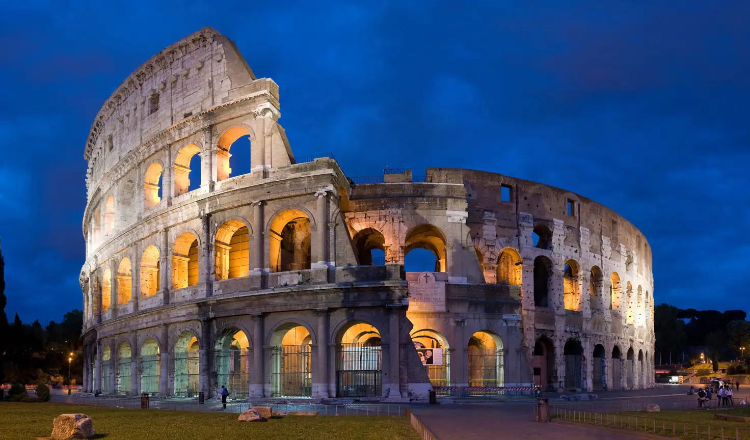 Coliseo antiguo romano iluminado al atardecer con arcos de piedra