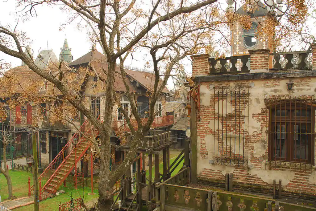 Edificios históricos de piedra con escaleras rojas y árboles antiguos