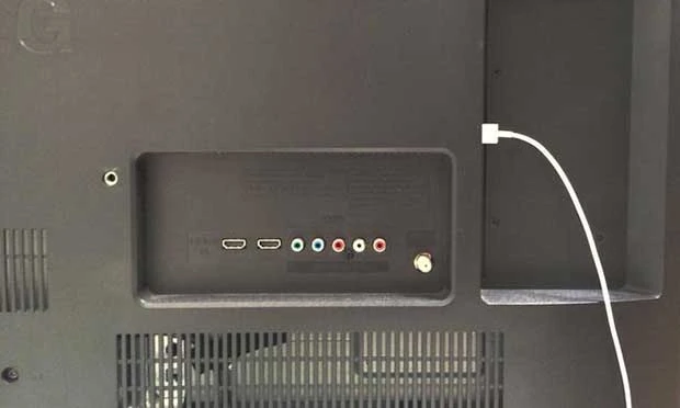 Panel trasero de un televisor con puertos HDMI y de audio, y un cable blanco conectado