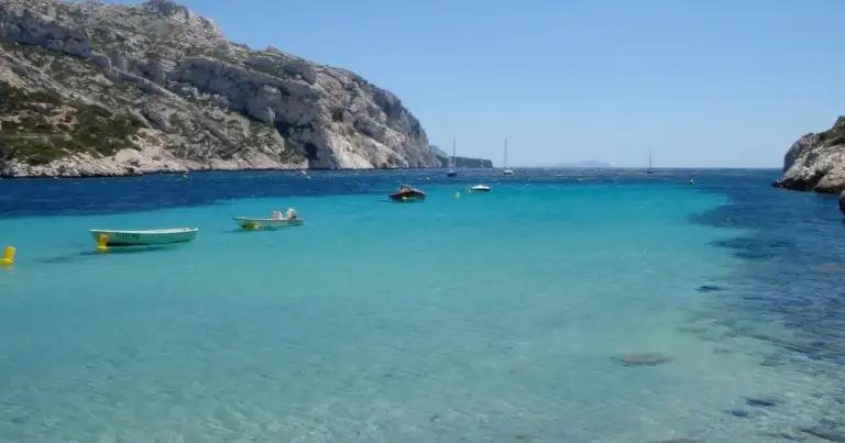 Cala de agua azul turquesa rodeada de acantilados rocosos y vegetación