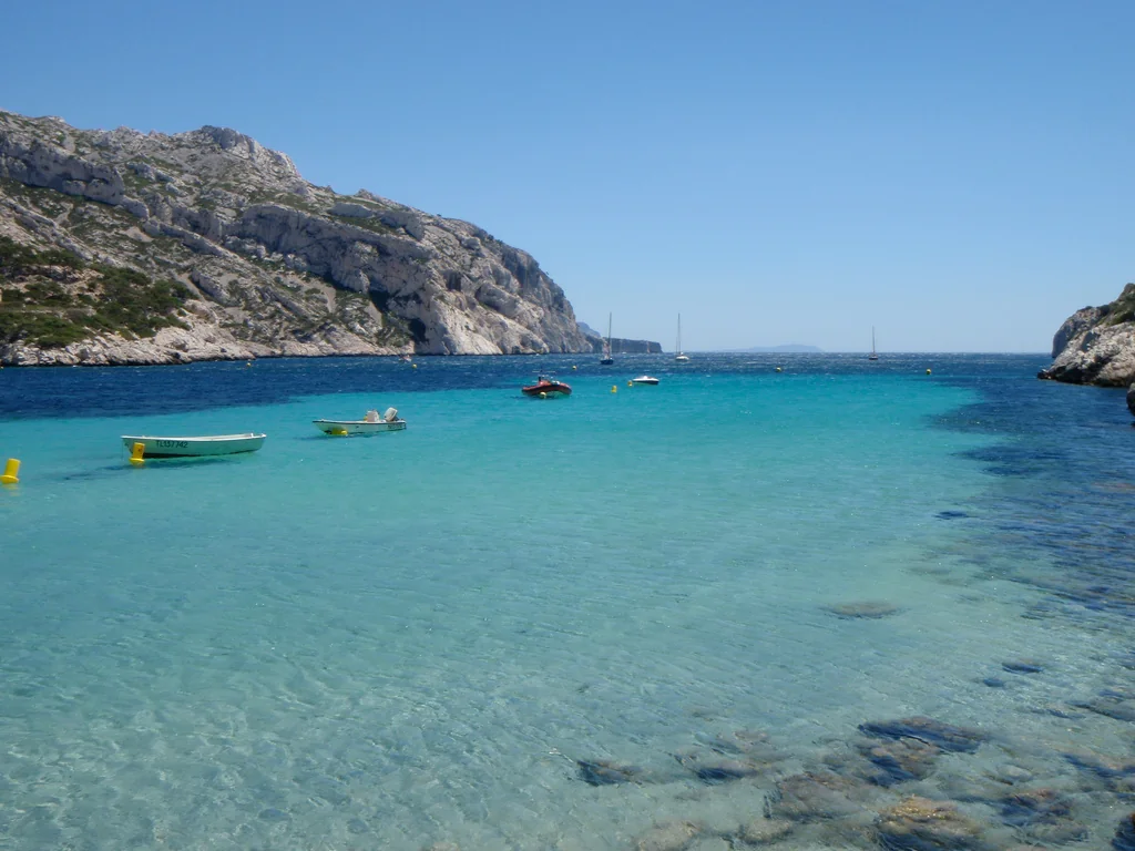 Cala de agua azul turquesa rodeada de acantilados rocosos y vegetación