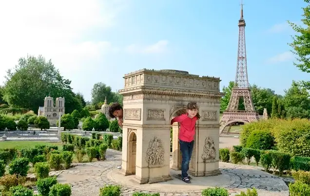 Niño tocando réplica miniatura con Torre Eiffel en parque temático de Francia