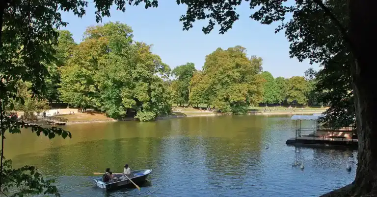 Río rodeado de árboles verdes con botes pequeños y arquitectura colonial