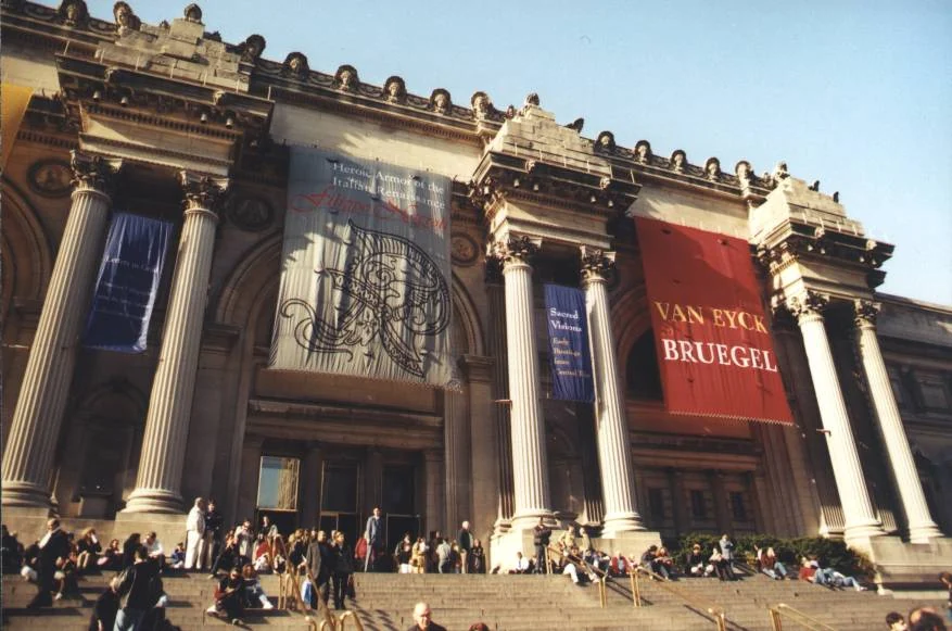 Fachada clásica de museo con columnas y visitantes ascendiendo escalones