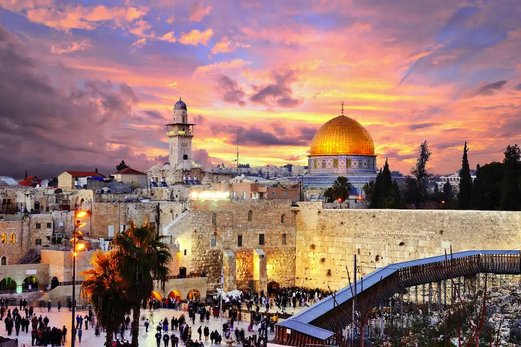 Ciudad Vieja de Jerusalén al atardecer con Cúpula de la Roca iluminada y peregrinos