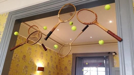 Raquetas de badminton decorativas colgadas sobre pared amarilla