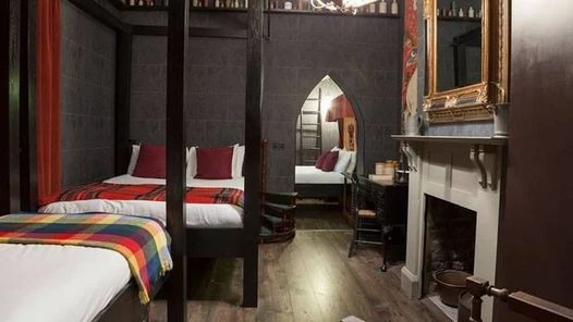 Dormitorio temático con cama de cuatro postes, decoración oscura y cortinas rojas
