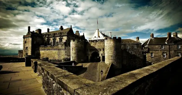 Castillo medieval de piedra gris con torres y almenas contra cielo nublado