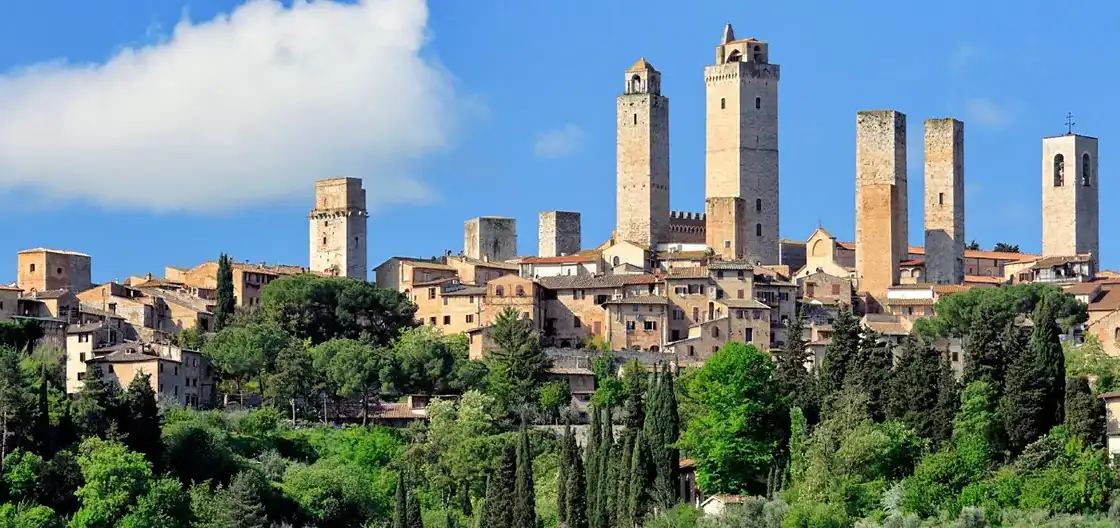 Plaza medieval rodeada de torres de piedra en San Gimignano bajo cielo azul
