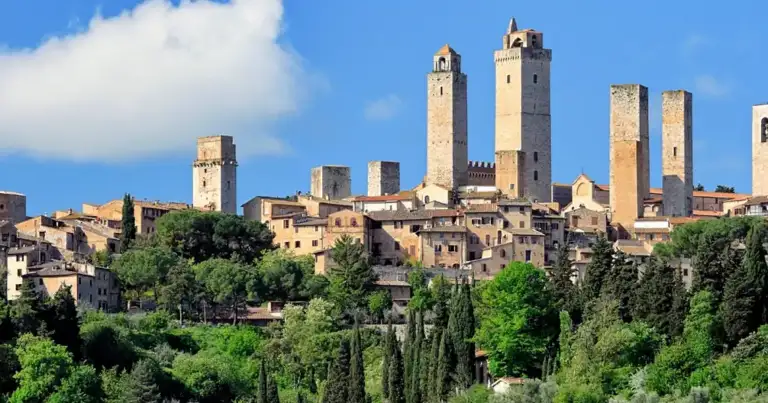 Plaza medieval rodeada de torres de piedra en San Gimignano bajo cielo azul