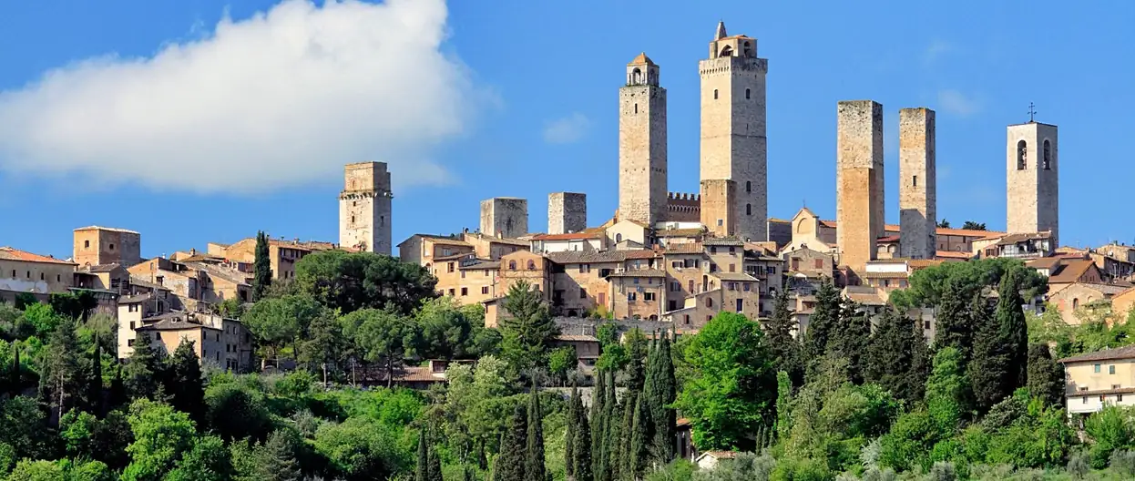 Plaza medieval rodeada de torres de piedra en San Gimignano bajo cielo azul