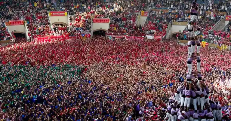 Multitud de personas formando torres humanas en plaza con banderas españolas