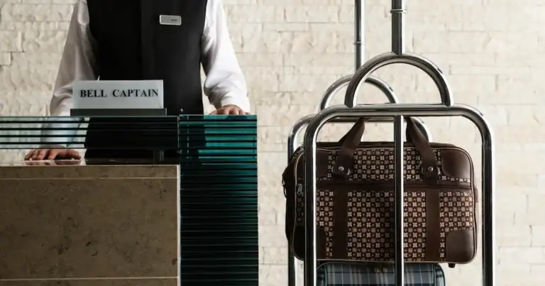 Recepcionista en mostrador de hotel con maletas y uniforme de servicio