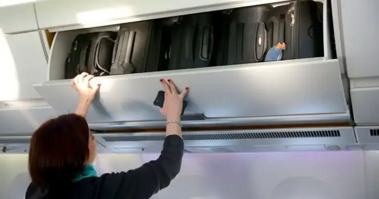 Pasajero guardando bolsa en compartimiento superior de avión