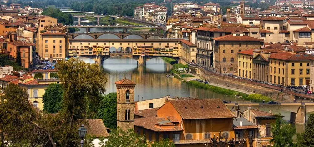 Ciudad histórica con puente medieval sobre río y edificios de terracota