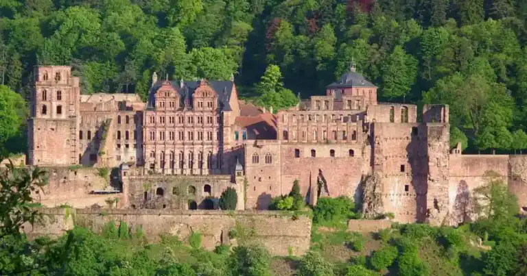 Ruinas de castillo rojo de piedra en bosque verde durante día soleado
