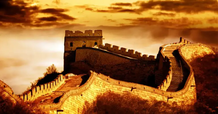 Muralla China serpenteando sobre montañas rocosas al atardecer dorado