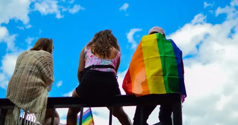 Personas con bandera LGBTQ+ durante un evento al aire libre