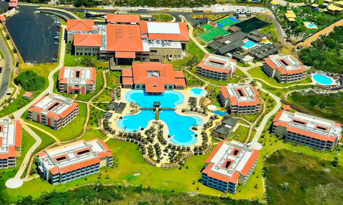Resort all inclusive en Brasil con piscina gigante y alojamiento de lujo Vista aérea de un resort all inclusive en Brasil con gran piscina central y edificios rodeados de jardines.