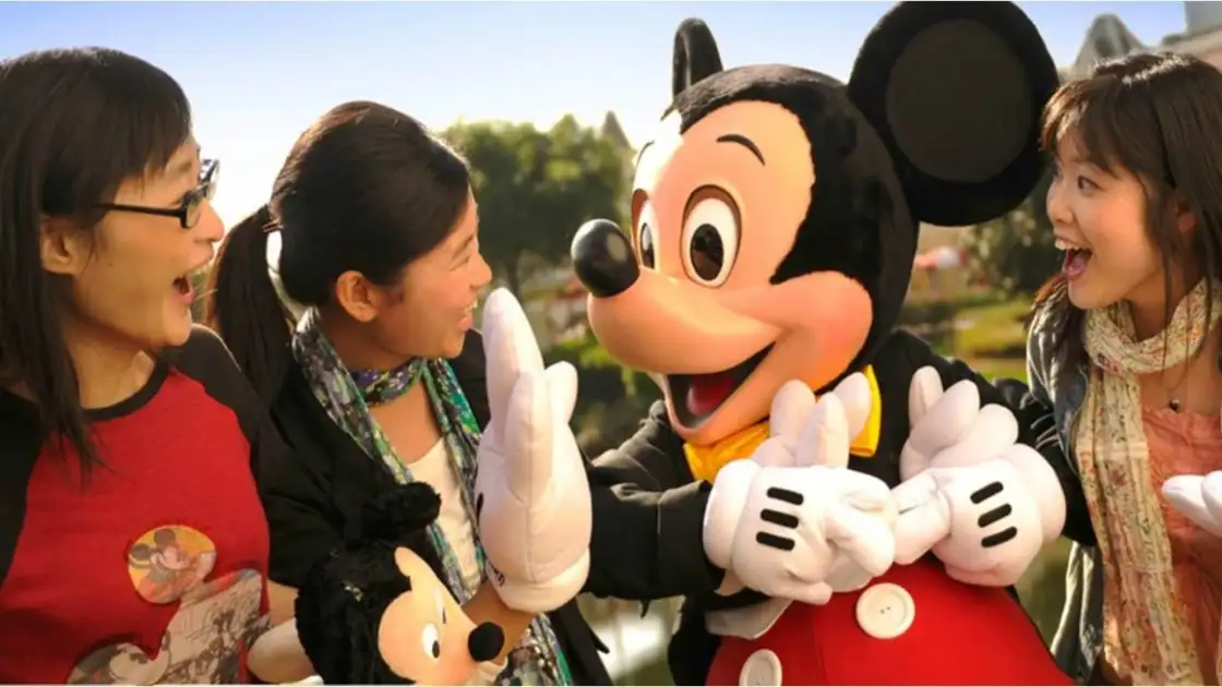 Mickey sonrie a unos niños que llevan un muñeco de mickey