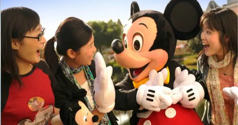 Mickey sonrie a unos niños que llevan un muñeco de mickey