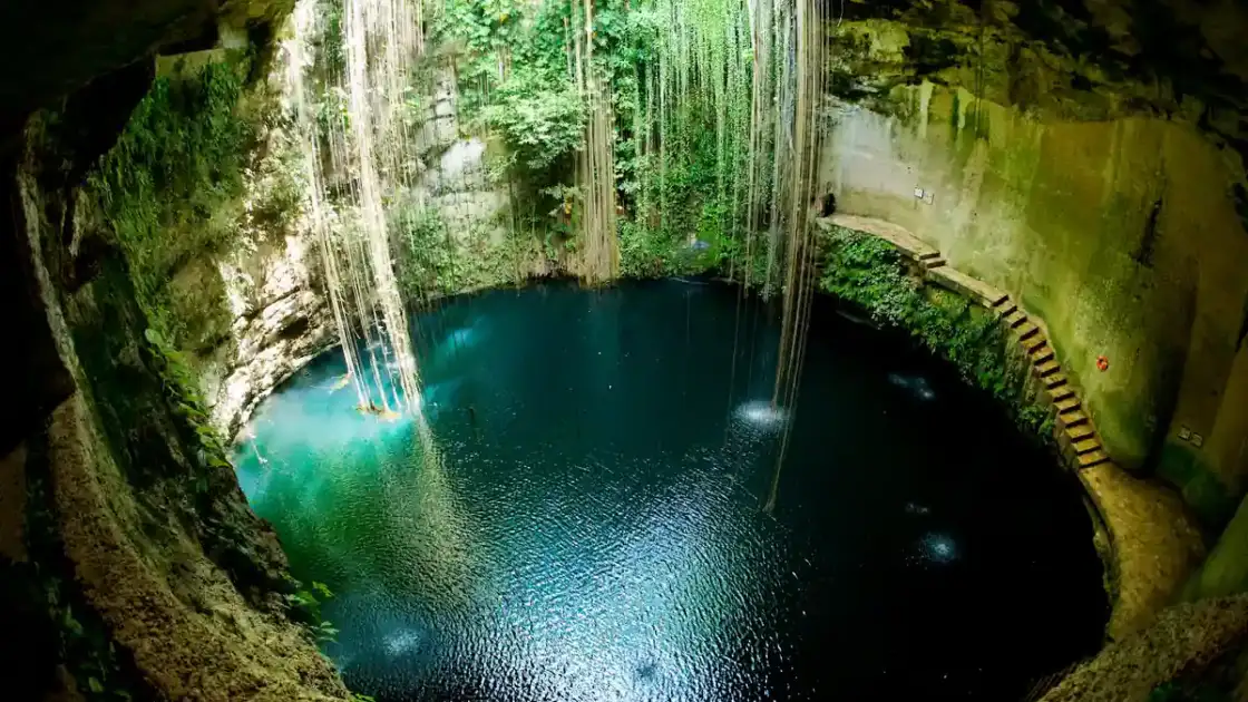 Cenote subterráneo lleno de agua turquesa con techo rocoso e iluminación