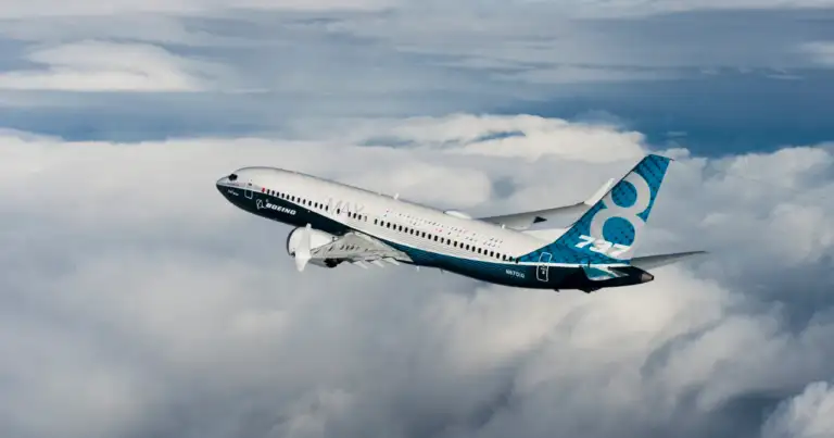 Avión Boeing con fuselaje azul volando entre nubes blancas en cielo despejado