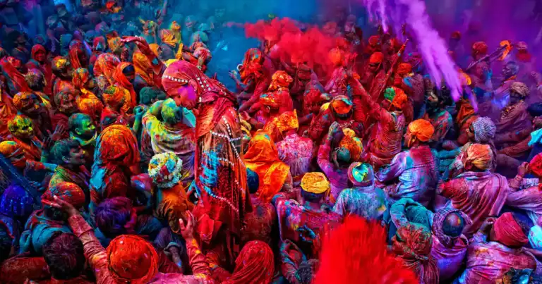 Multitud de personas cubiertas de polvos de colores brillantes en celebración