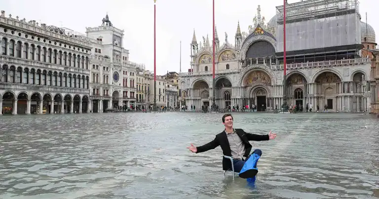 plaza San Marcos en Venecia inundada por la marea alta y un hombre flota en una silla