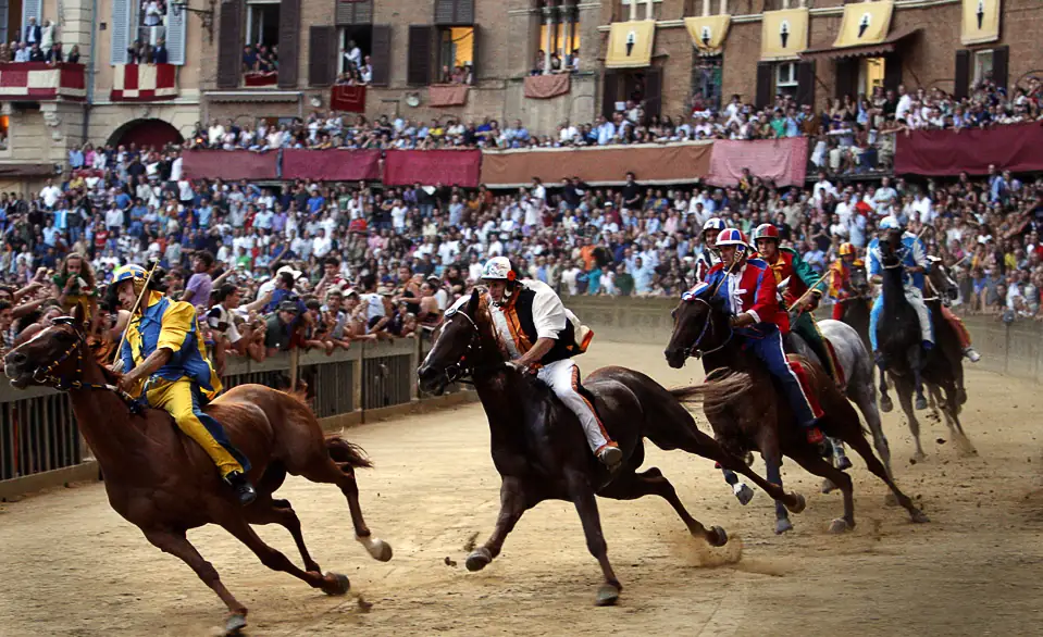 Carrera de caballos el Palio en plaza medieval de Siena con multitudes de espectadores
