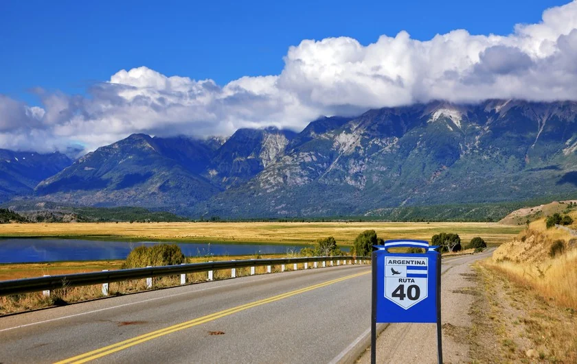 Carretera con señal de Ruta 40 atravesando valle montañoso verde