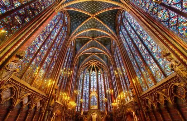 Interior de capilla gótica con bóveda decorada y vitrales coloridos