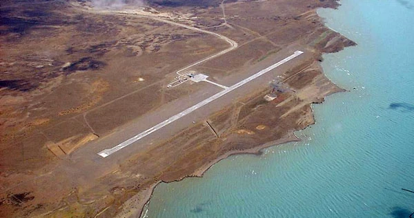 Pista de aterrizaje en zona árida junto a agua turquesa