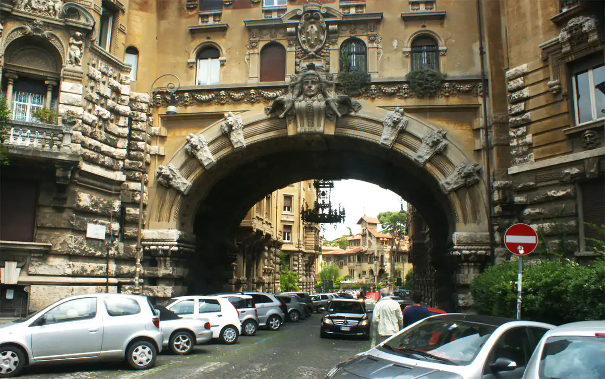 Arco arquitectónico de piedra con coches en calle romana