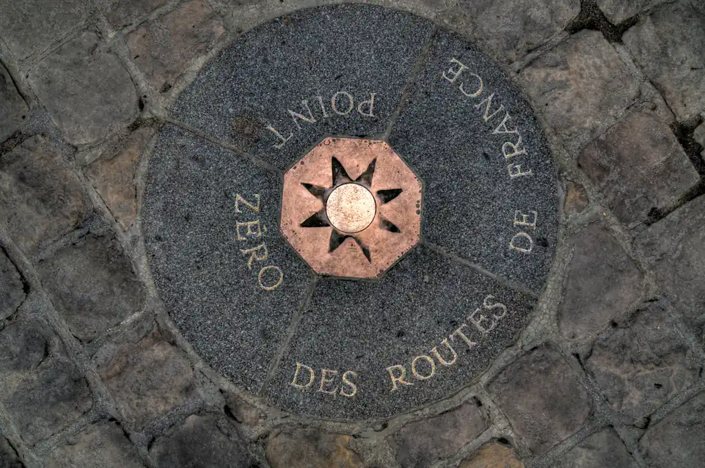 Marcador circular en suelo de piedra con inscripción de punto cero