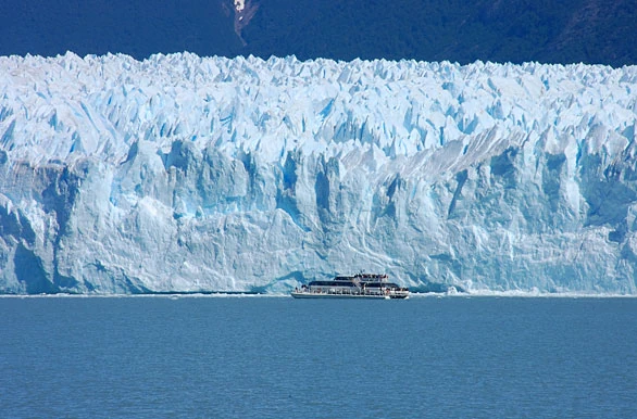 Glaciar de hielo blanco sobre agua azul con barco de turismo