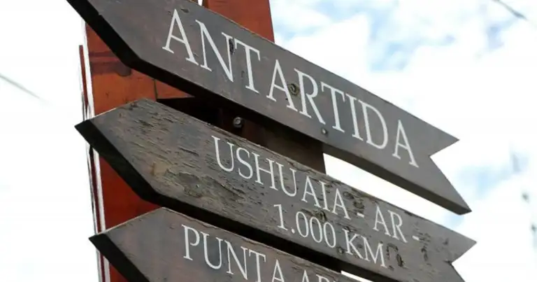 Señal de direcciones con inscripciones 'Antártida', 'Ushuaia' y distancias en kilómetros