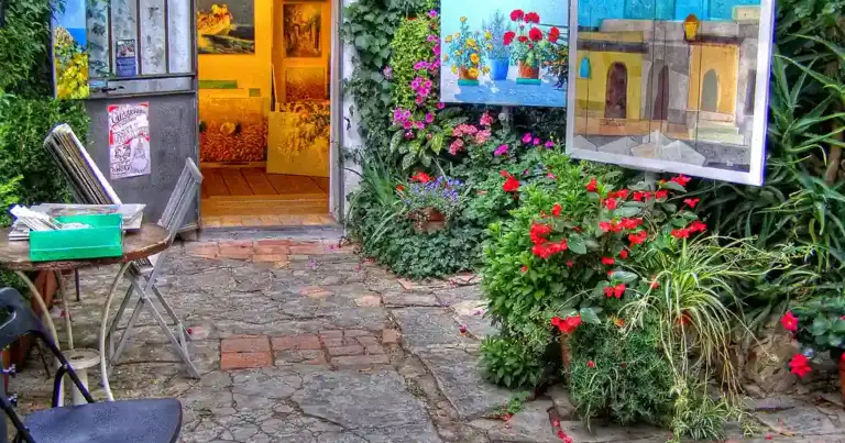 Tienda de arte con puerta amarilla en aldea rodeada de flores de colores