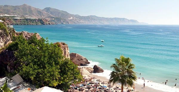 Barcos amarrados, palmeras y arena en una playa de la Costa del Sol, Málaga