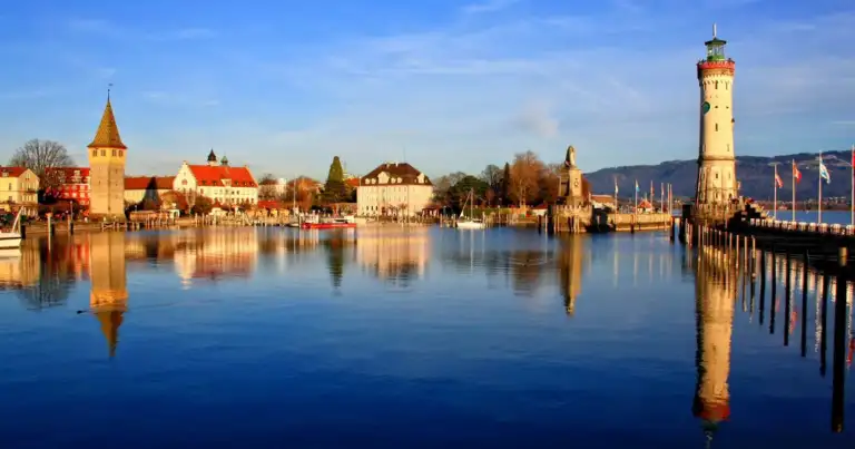 Ciudadela medieval y torres reflejadas en lago tranquilo al atardecer azul