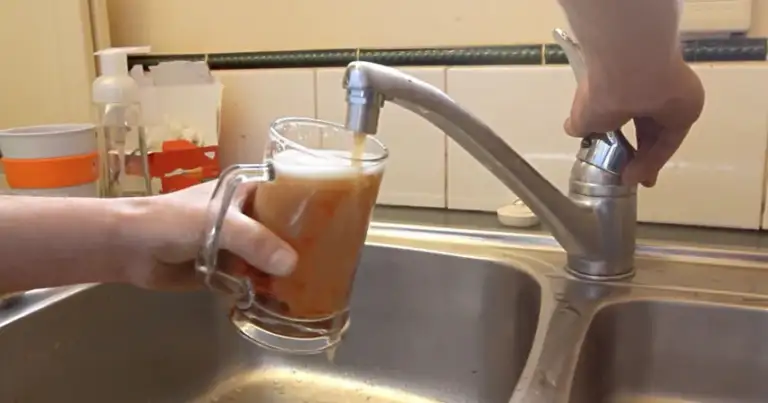 sirviendo cerveza desde la canilla de un hogar. Hay una mano con un vaso y sale cerveza de la canilla