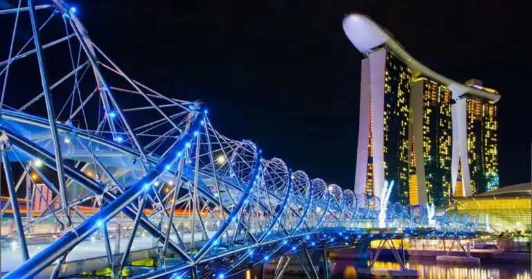 Estructura moderna iluminada junto a agua reflejada de noche en ciudad asiática
